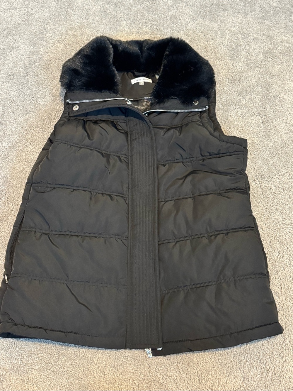 Calvin Klein puffer vest features a cozy faux fur collar and a functional zip cl